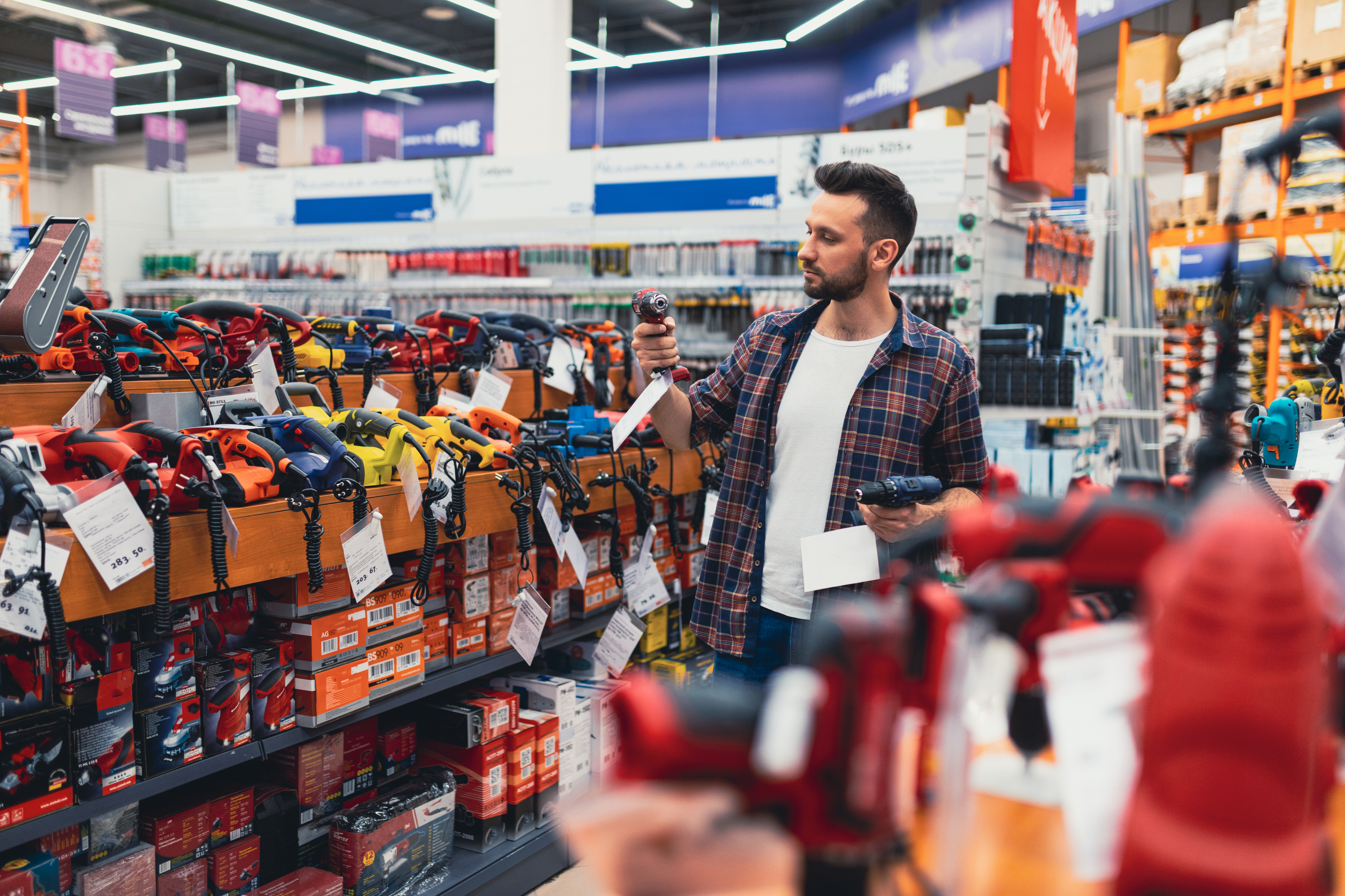 a customer in a hardware store compares two screwdrivers