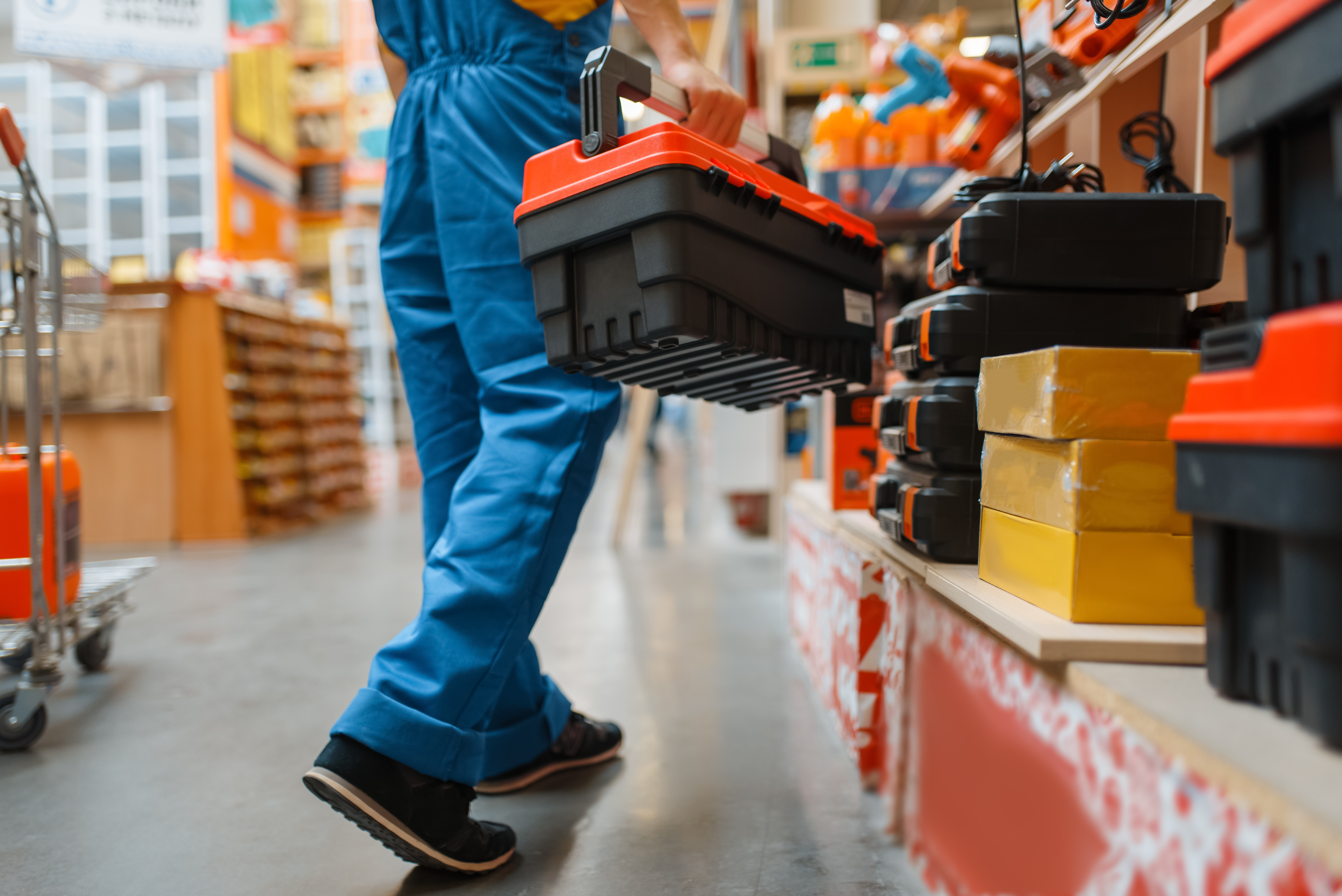 Builder with toolbox at the shelf, hardware store