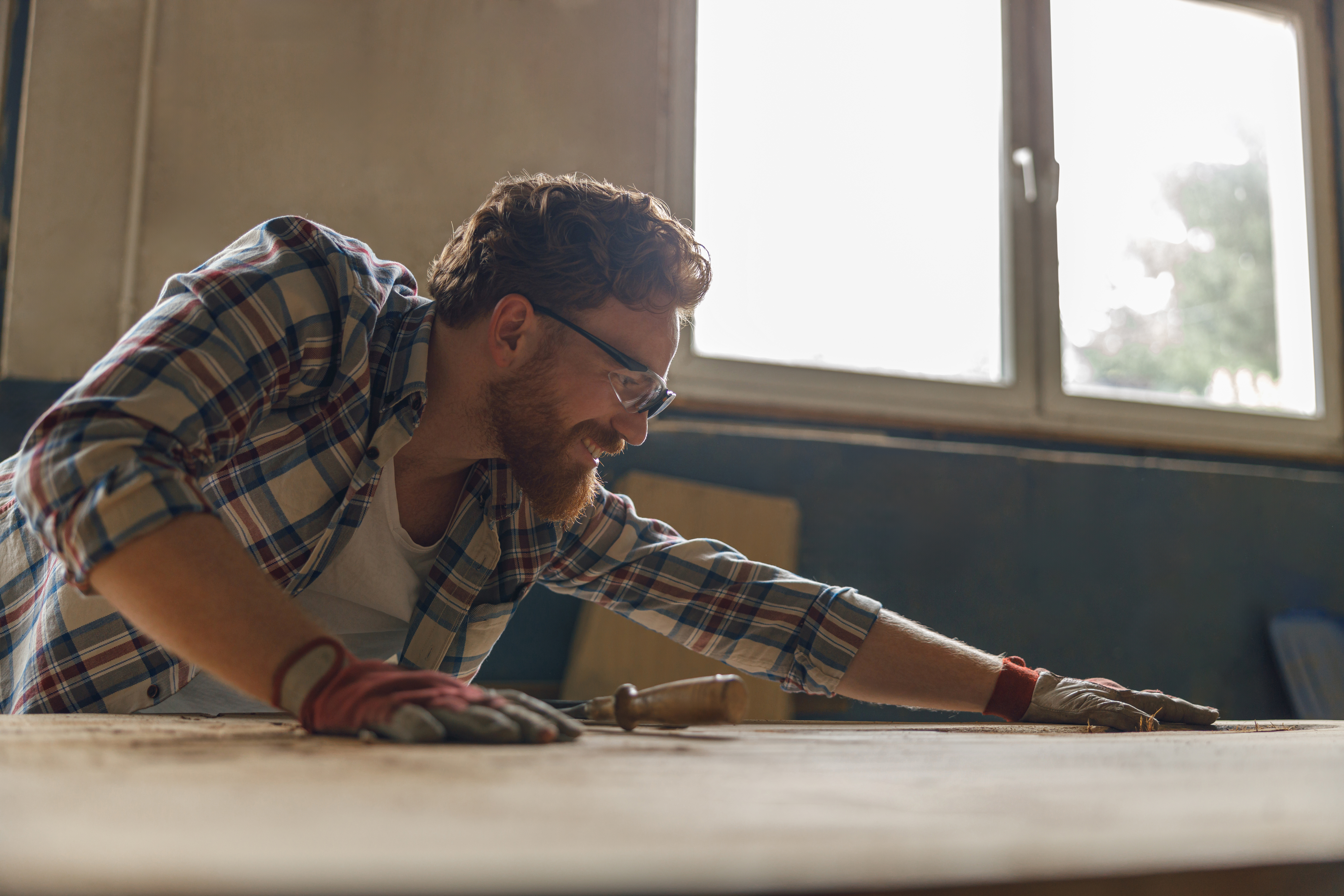 Professional craftsman working with chisel while cutting wooden plank in carpentry workshop